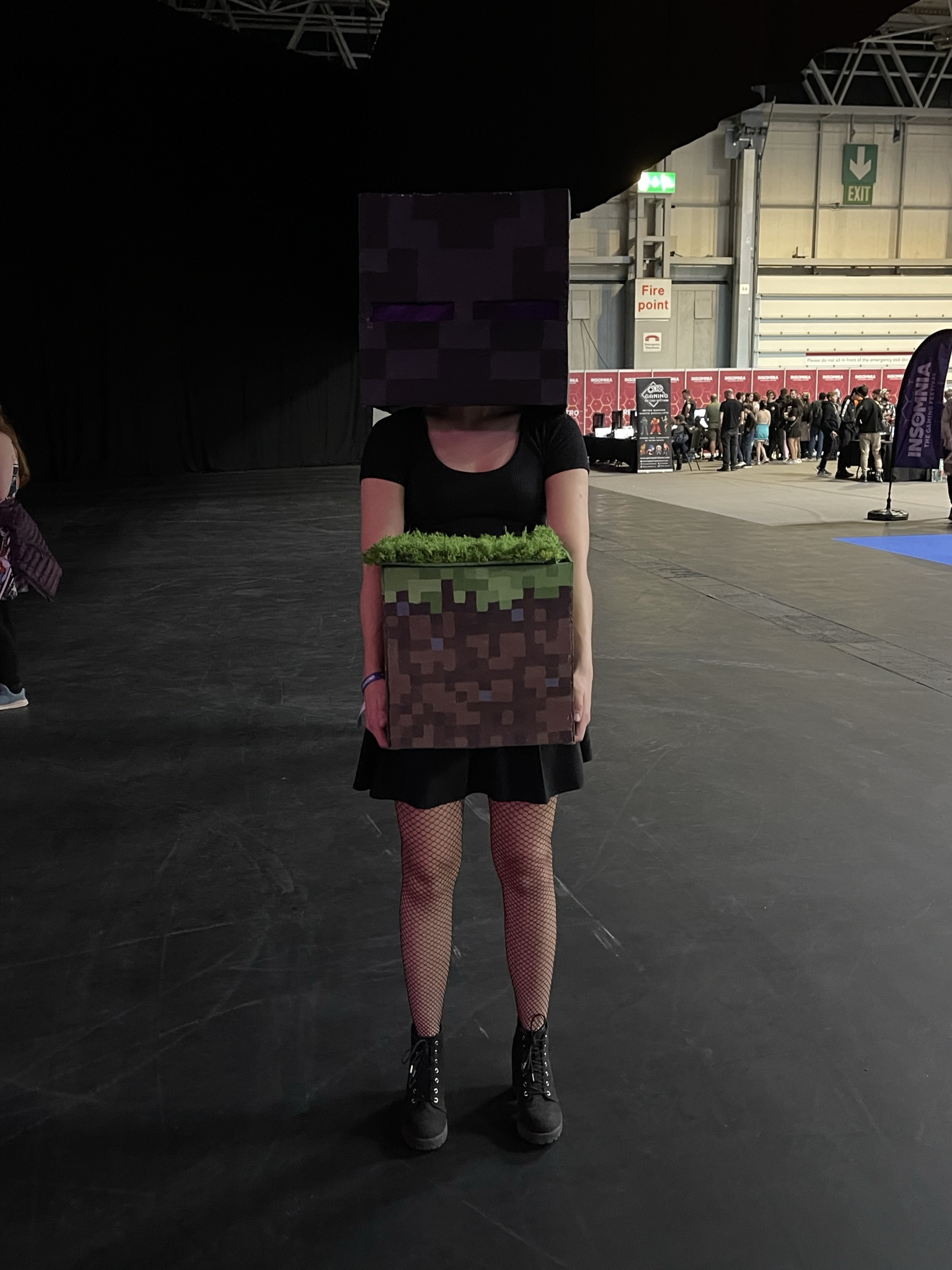 Cosplayer dressed in a black dress with an endermen head holding a minecraft block.